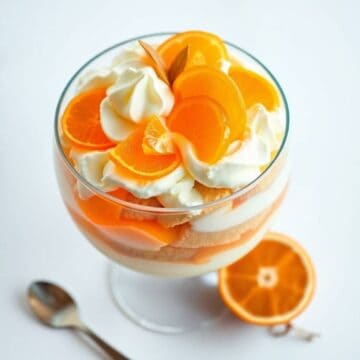 Delicious creamsicle trifle with layers of whipped cream, orange slices, and sponge cake. Perfect fo.